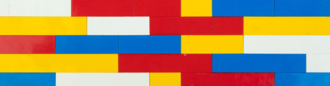 A LEGO brick wall made from red, blue, white, and yellow bricks